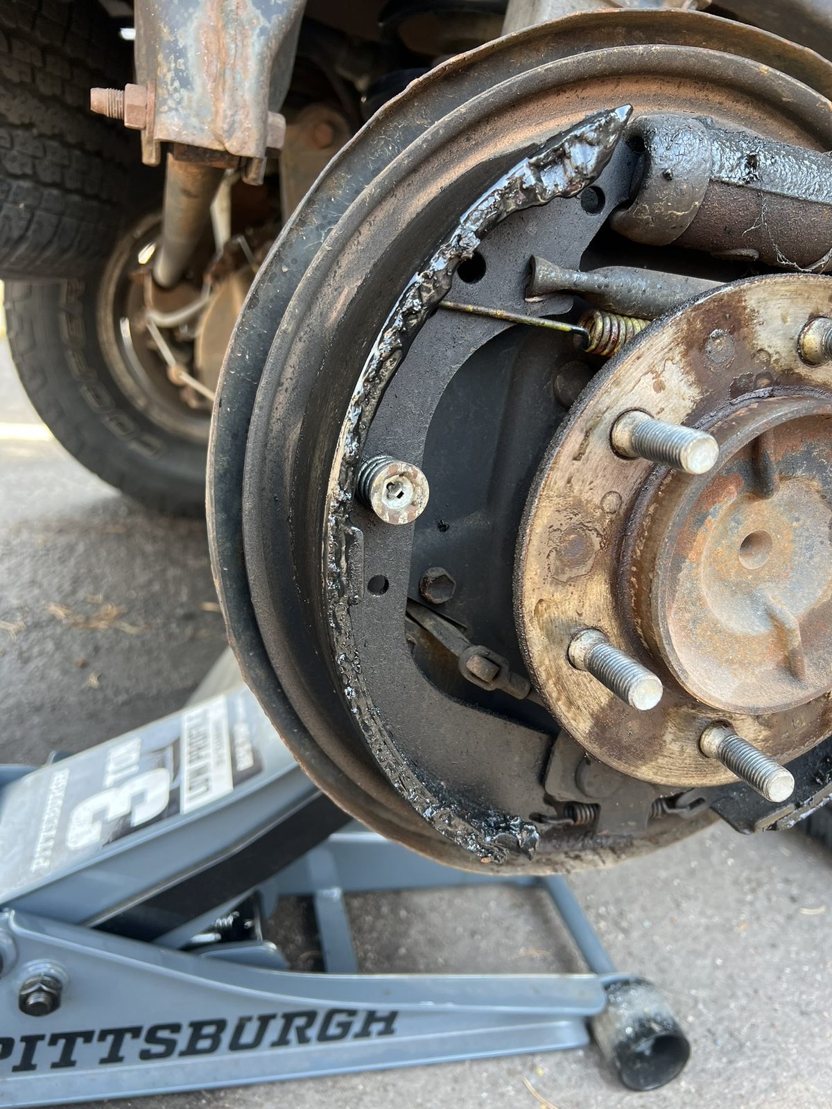 Leaking rear drum brake assembly being replaced on jack stands